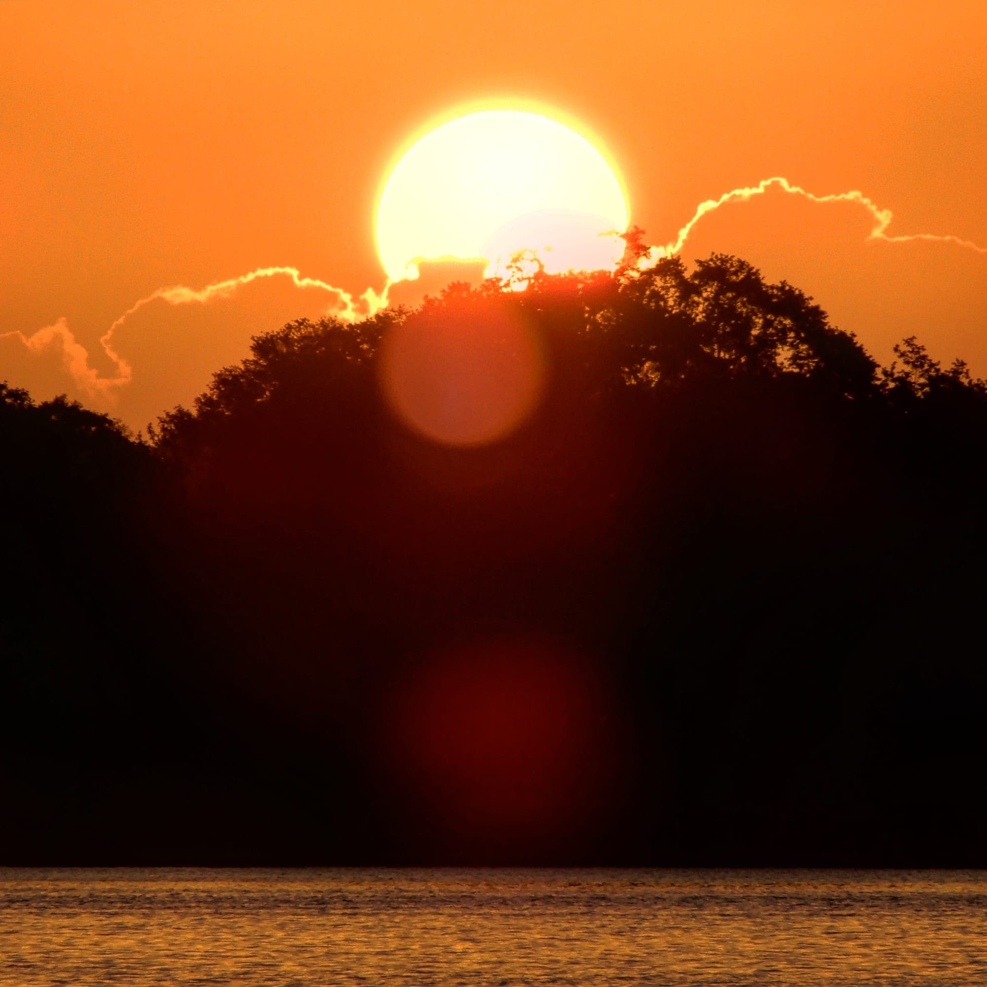 Sunrise burning orange over the still water of Lake Howard