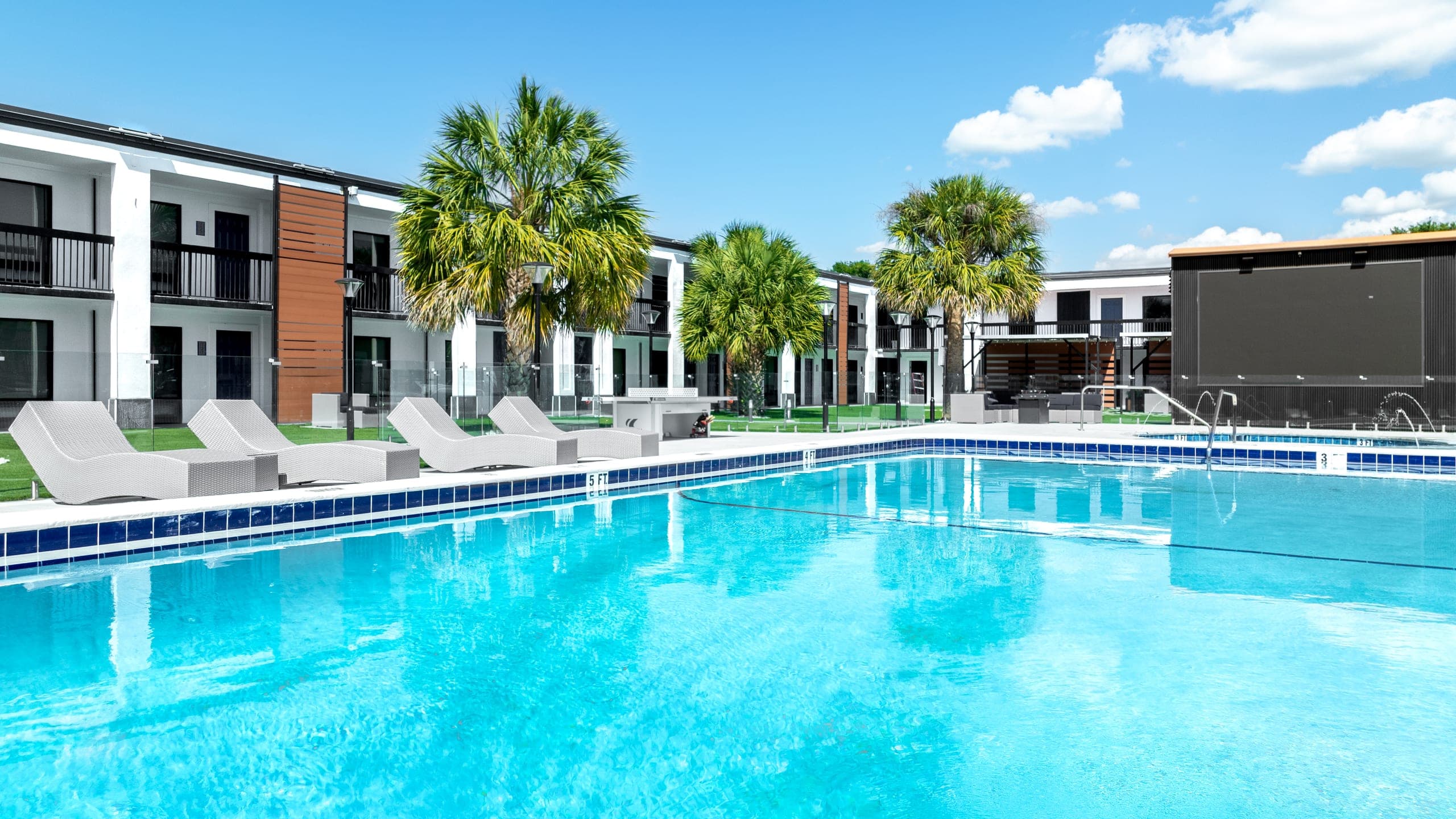 The resort pool at The Jade, with lounge chairs and palms along the deck and the residence buildings beyond