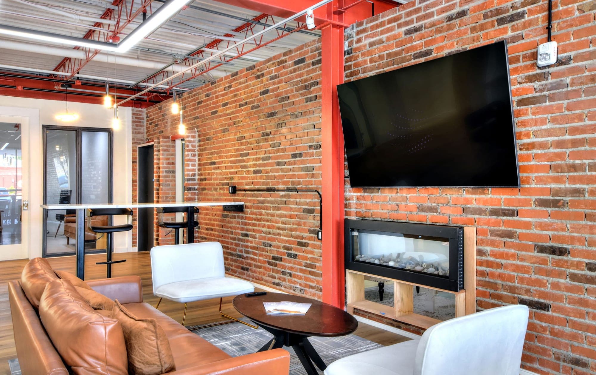 The leasing lounge at The Jade, with leather seating and a brick fireplace wall