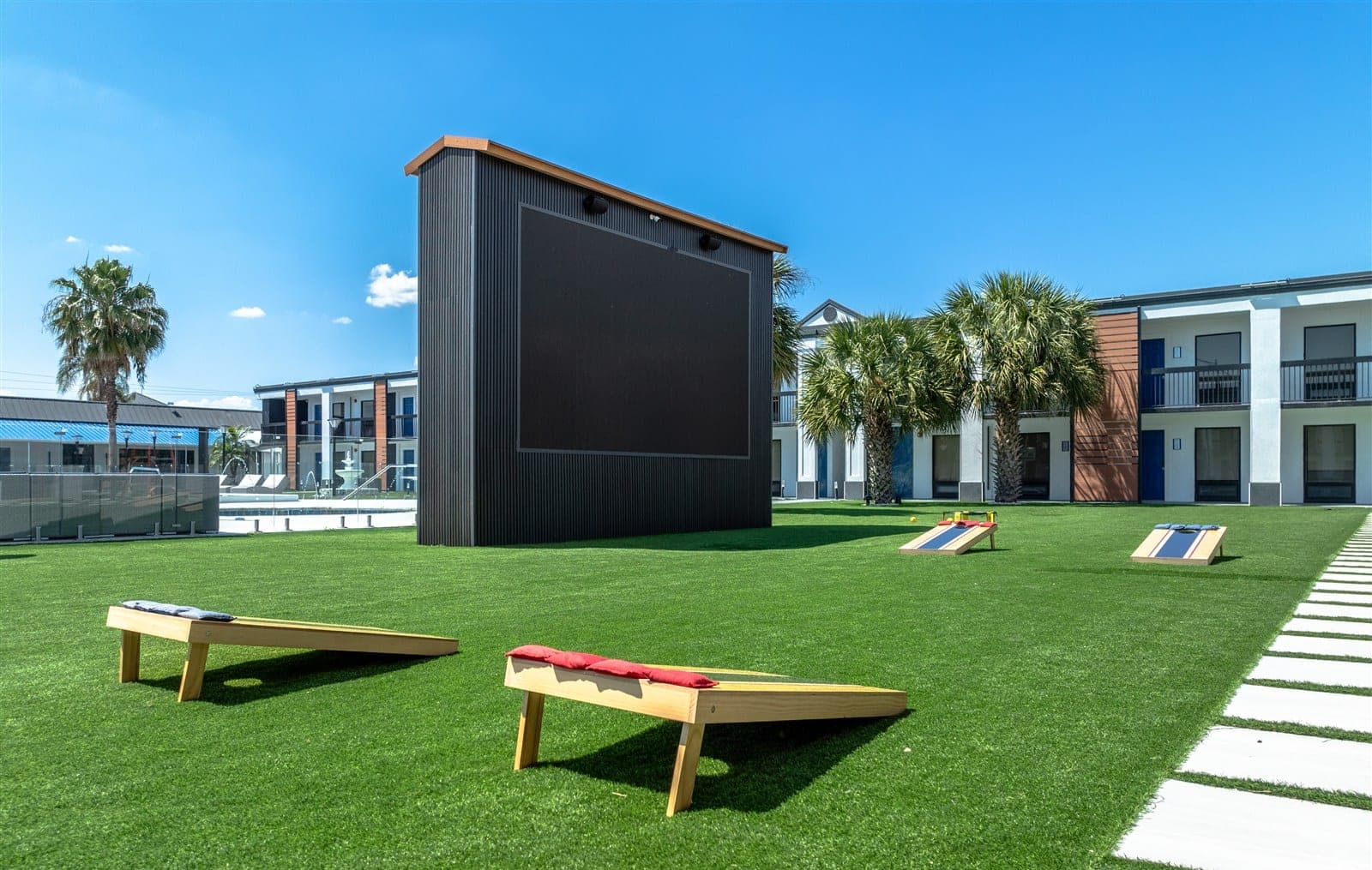 The Jade's outdoor theater and cornhole lawn, surrounded by palms and courtyard homes